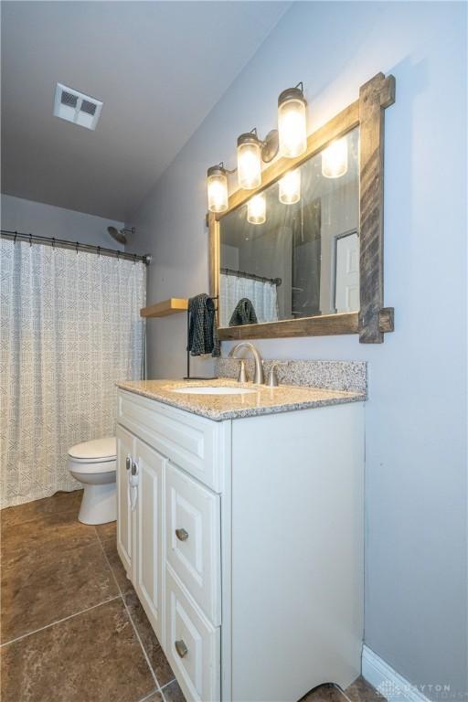 bathroom featuring toilet, vanity, and visible vents