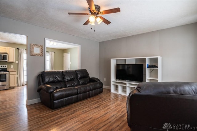 living area with a textured ceiling, baseboards, ceiling fan, and wood finished floors
