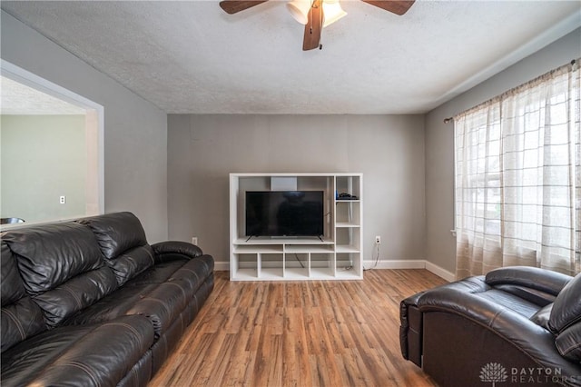 living area with baseboards, wood finished floors, ceiling fan, and a textured ceiling