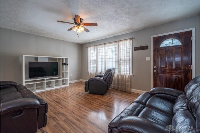 living area featuring plenty of natural light, wood finished floors, ceiling fan, and a textured ceiling