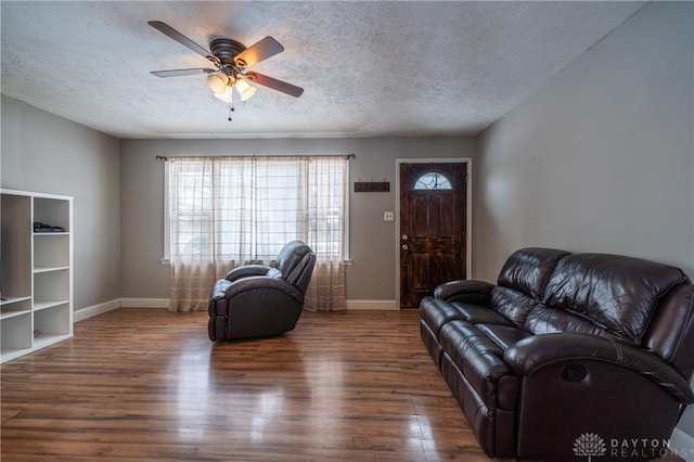 living room with a textured ceiling, baseboards, ceiling fan, and wood finished floors