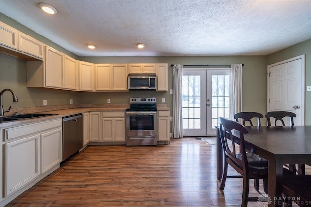 kitchen with light countertops, french doors, stainless steel appliances, a sink, and dark wood-style floors