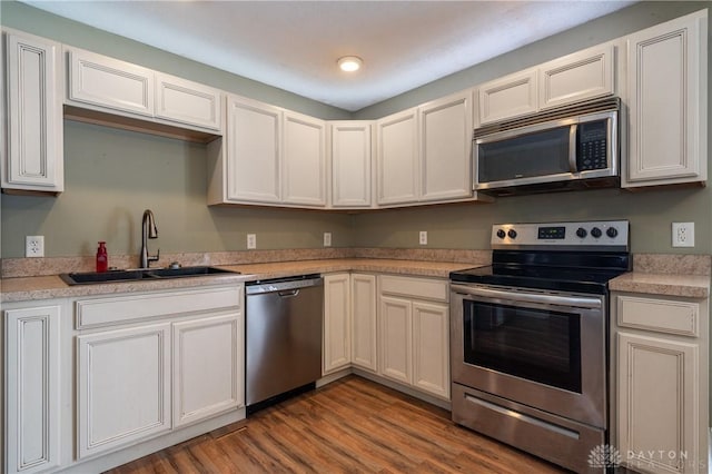 kitchen with light countertops, a sink, stainless steel appliances, and wood finished floors