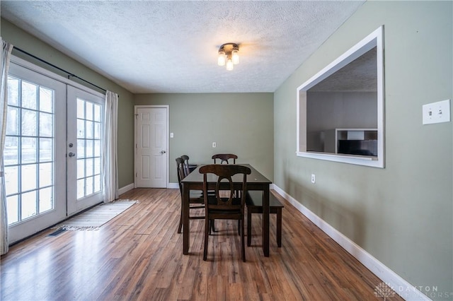 dining area featuring baseboards, wood finished floors, french doors, and a textured ceiling