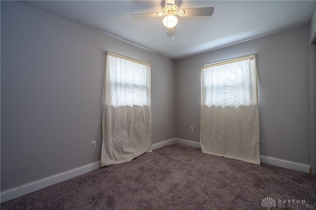 carpeted spare room featuring baseboards, a ceiling fan, and plenty of natural light
