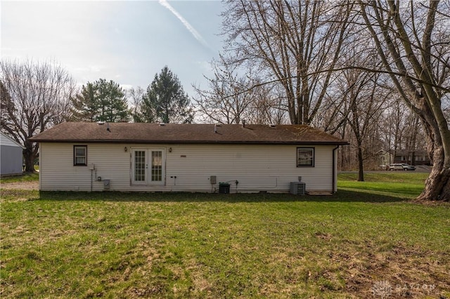rear view of house featuring a lawn, central AC unit, and french doors