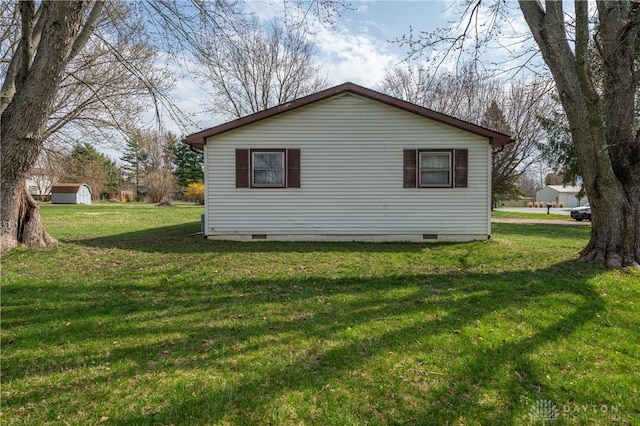 view of side of property with an outdoor structure, crawl space, and a yard