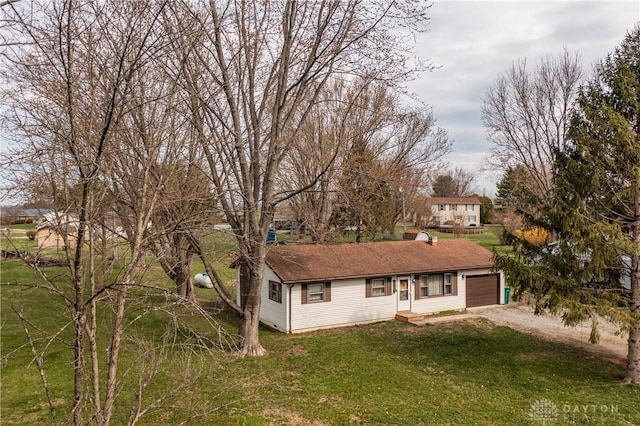 ranch-style home featuring driveway, an attached garage, and a front yard
