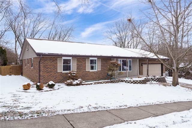 ranch-style house featuring an attached garage, fence, and brick siding