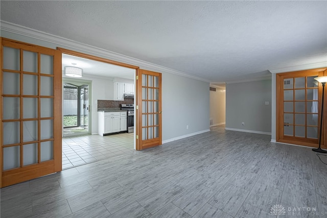 spare room featuring visible vents, ornamental molding, a textured ceiling, french doors, and light wood-style floors