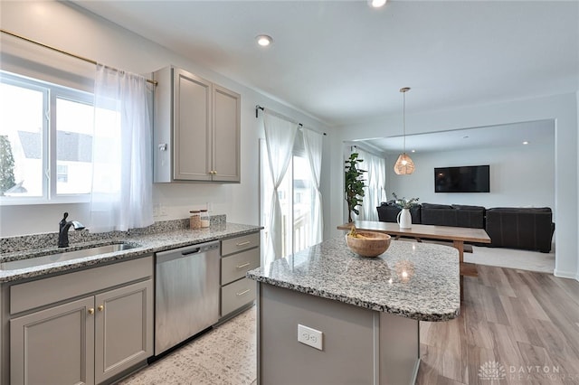 kitchen featuring gray cabinets, a sink, open floor plan, and stainless steel dishwasher