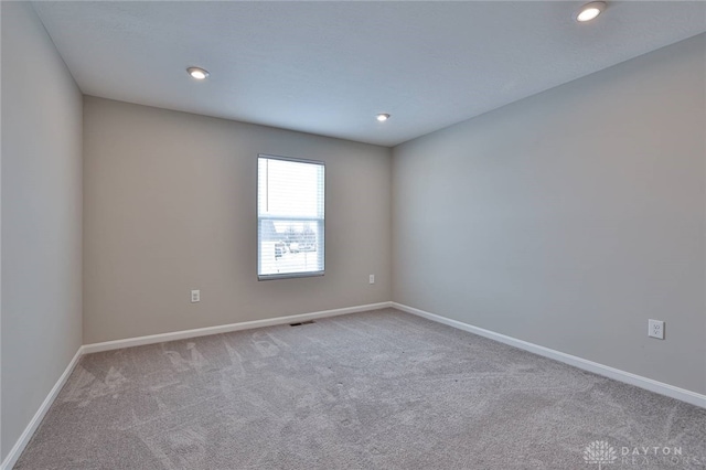 spare room with baseboards, recessed lighting, and light colored carpet