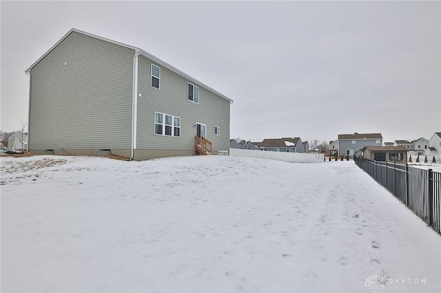 snow covered rear of property featuring crawl space, a residential view, fence, and entry steps