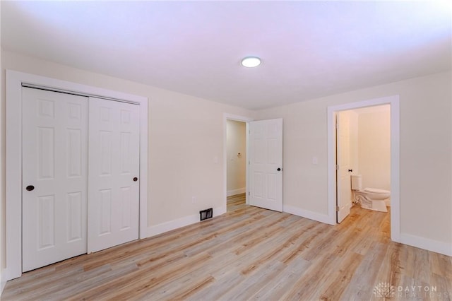 unfurnished bedroom with light wood finished floors, baseboards, a closet, and ensuite bathroom