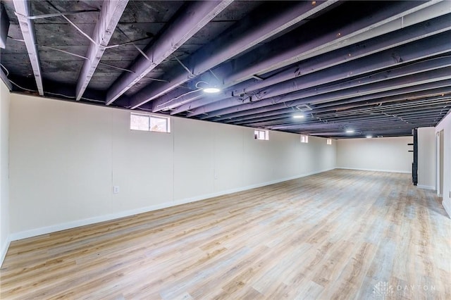 basement with baseboards and light wood-style floors