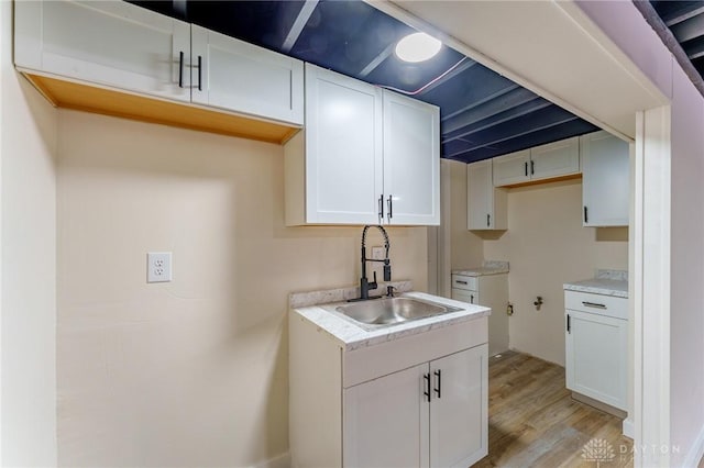 laundry area featuring light wood-type flooring, cabinet space, and a sink