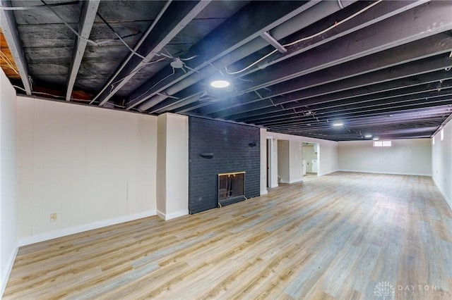 basement featuring a brick fireplace and wood finished floors