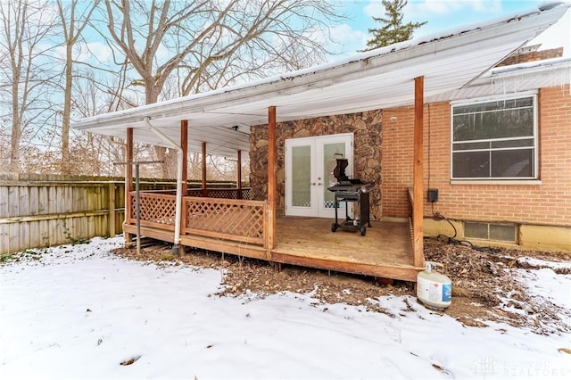 snow covered deck featuring french doors, grilling area, and fence