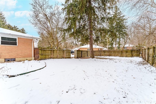 yard layered in snow with a fenced backyard