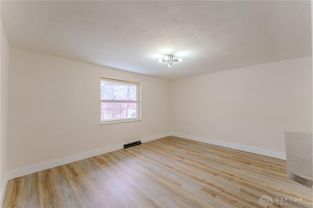 spare room featuring light wood-style flooring, visible vents, and baseboards