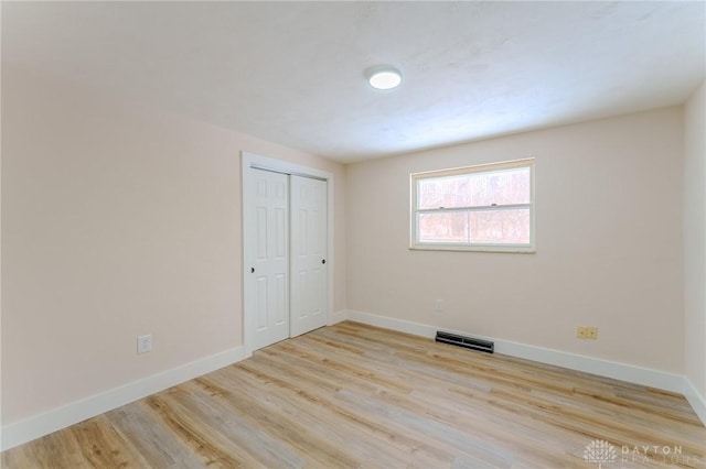 unfurnished bedroom with a closet, visible vents, light wood-style flooring, and baseboards