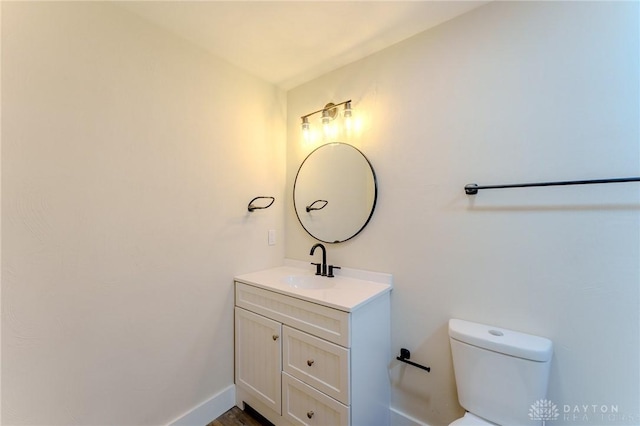 half bathroom featuring baseboards, vanity, and toilet