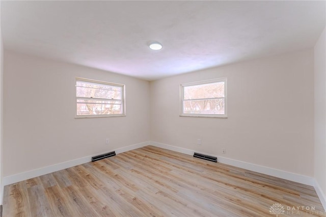 empty room with light wood-style floors, a healthy amount of sunlight, and visible vents