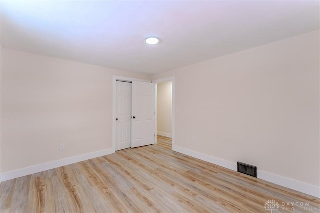 unfurnished room with light wood-style flooring, visible vents, and baseboards