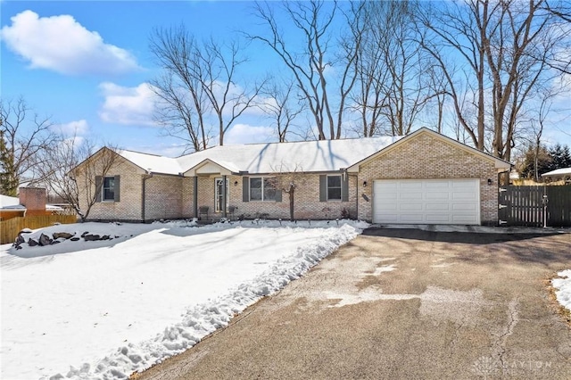 single story home with a garage, aphalt driveway, fence, and brick siding