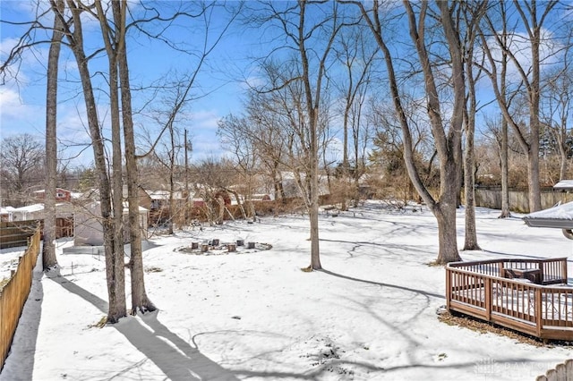 snowy yard with a wooden deck and fence