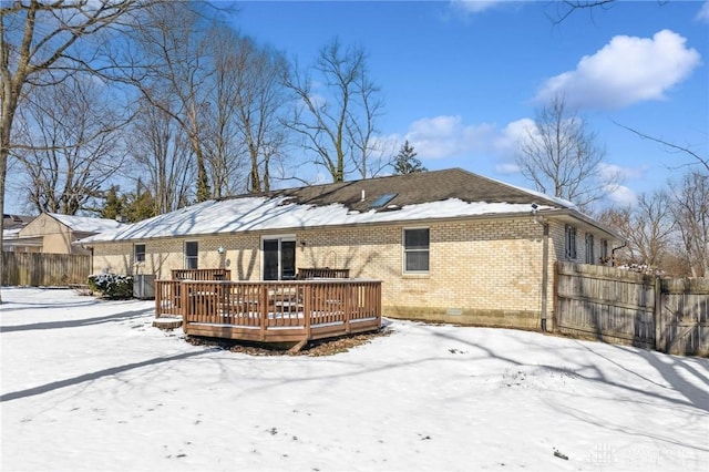 snow covered property with crawl space, brick siding, fence, and a deck