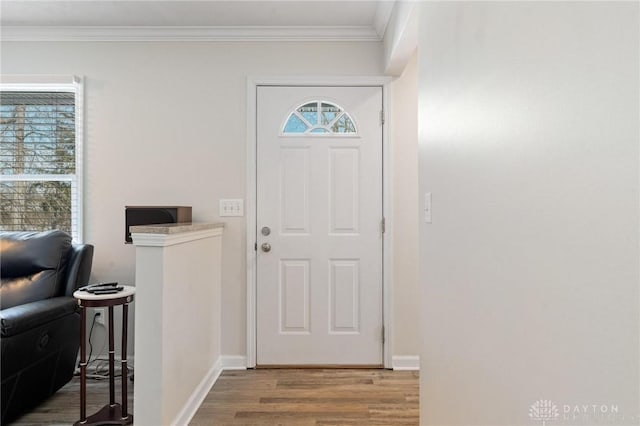 foyer featuring light wood-type flooring, crown molding, and baseboards