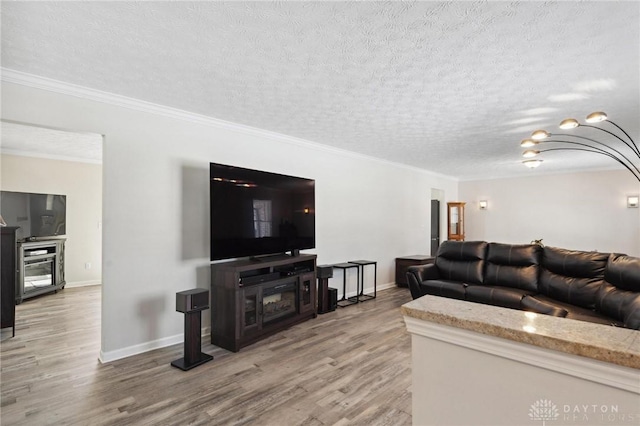 living area with a textured ceiling, ornamental molding, and light wood-style floors