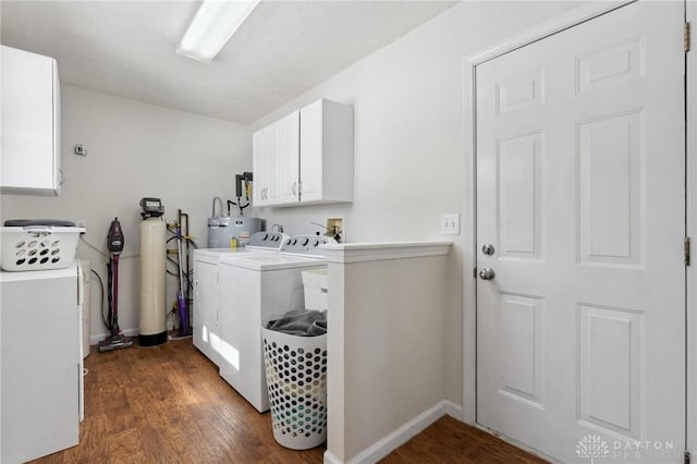 laundry room with washing machine and clothes dryer, electric water heater, baseboards, cabinet space, and dark wood finished floors