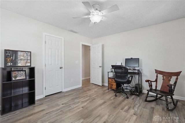 office space featuring a ceiling fan, visible vents, baseboards, and wood finished floors