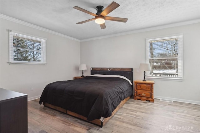 bedroom with light wood-style floors, a textured ceiling, baseboards, and crown molding