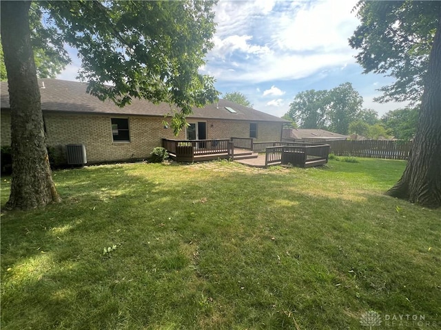 view of yard with fence, a deck, and central AC