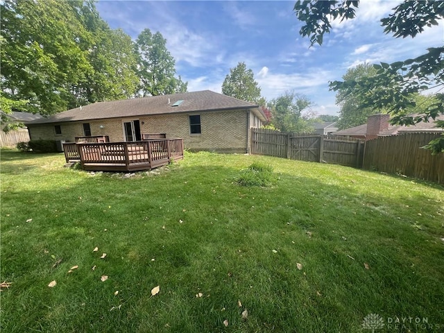 back of house featuring a yard, brick siding, a fenced backyard, and a wooden deck