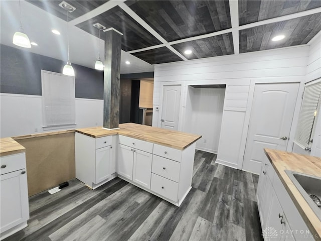 kitchen featuring dark wood finished floors, decorative light fixtures, white cabinetry, wooden counters, and a sink