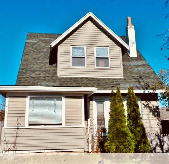 view of front of property with a chimney, fence, and roof with shingles