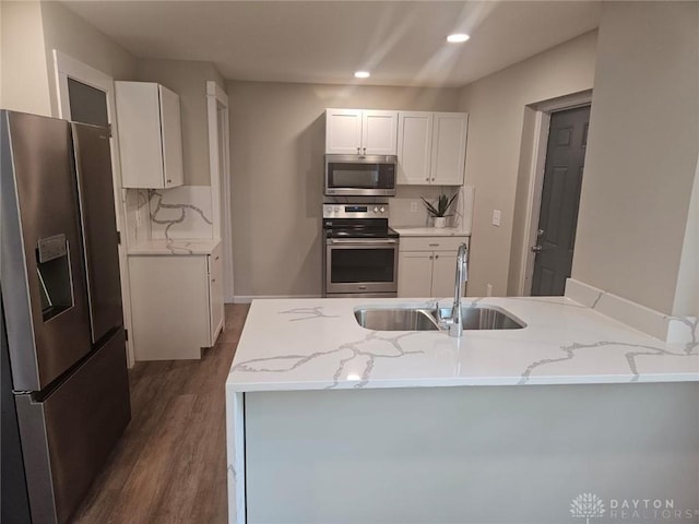 kitchen featuring stainless steel appliances, white cabinets, a sink, and light stone counters