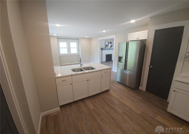 kitchen with light countertops, dark wood-type flooring, white cabinetry, a sink, and stainless steel fridge