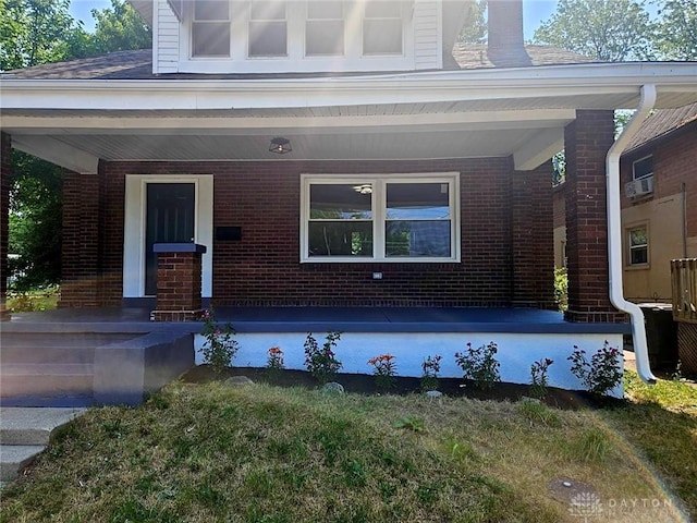 property entrance with a porch and brick siding