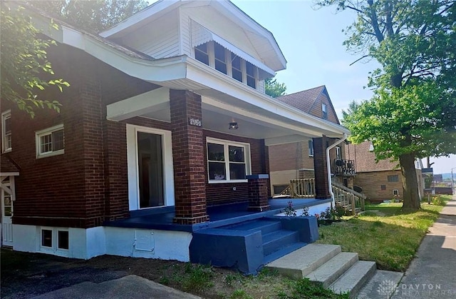 exterior space with a porch and brick siding