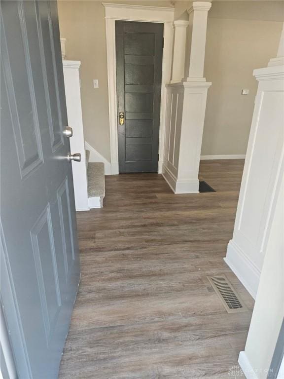 interior space featuring wood finished floors, stairway, decorative columns, and visible vents