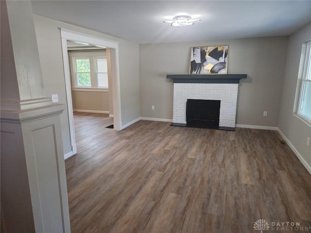 unfurnished living room featuring a fireplace, baseboards, and wood finished floors