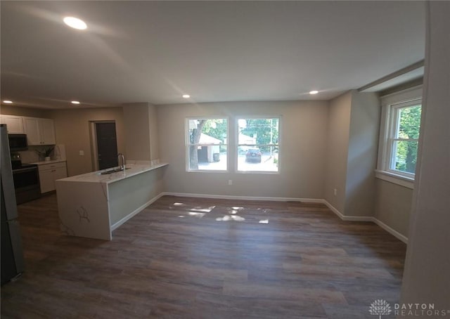 interior space featuring electric range, white cabinets, a peninsula, a sink, and recessed lighting