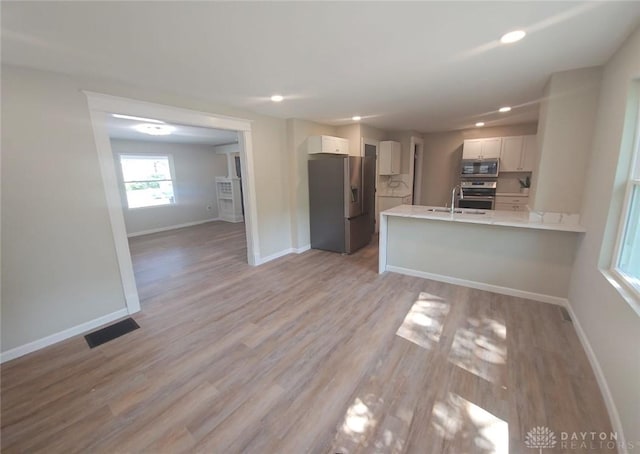 interior space featuring light wood finished floors, baseboards, visible vents, a sink, and recessed lighting