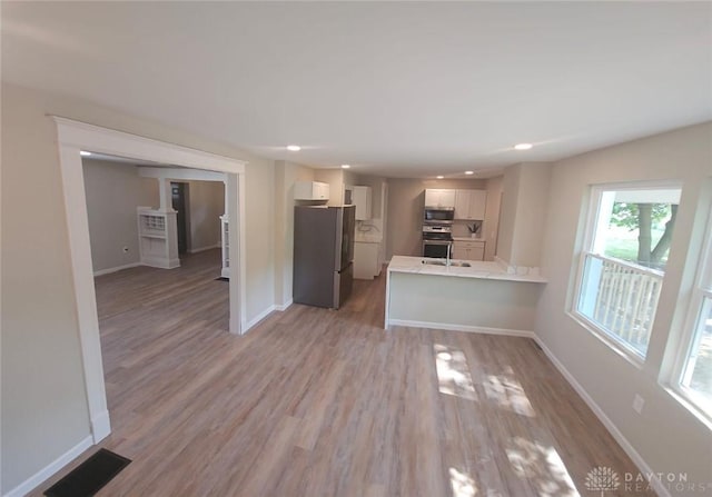 kitchen with a peninsula, visible vents, baseboards, white cabinets, and appliances with stainless steel finishes