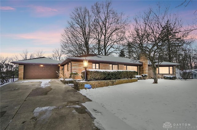 mid-century modern home featuring driveway, a chimney, and an attached garage